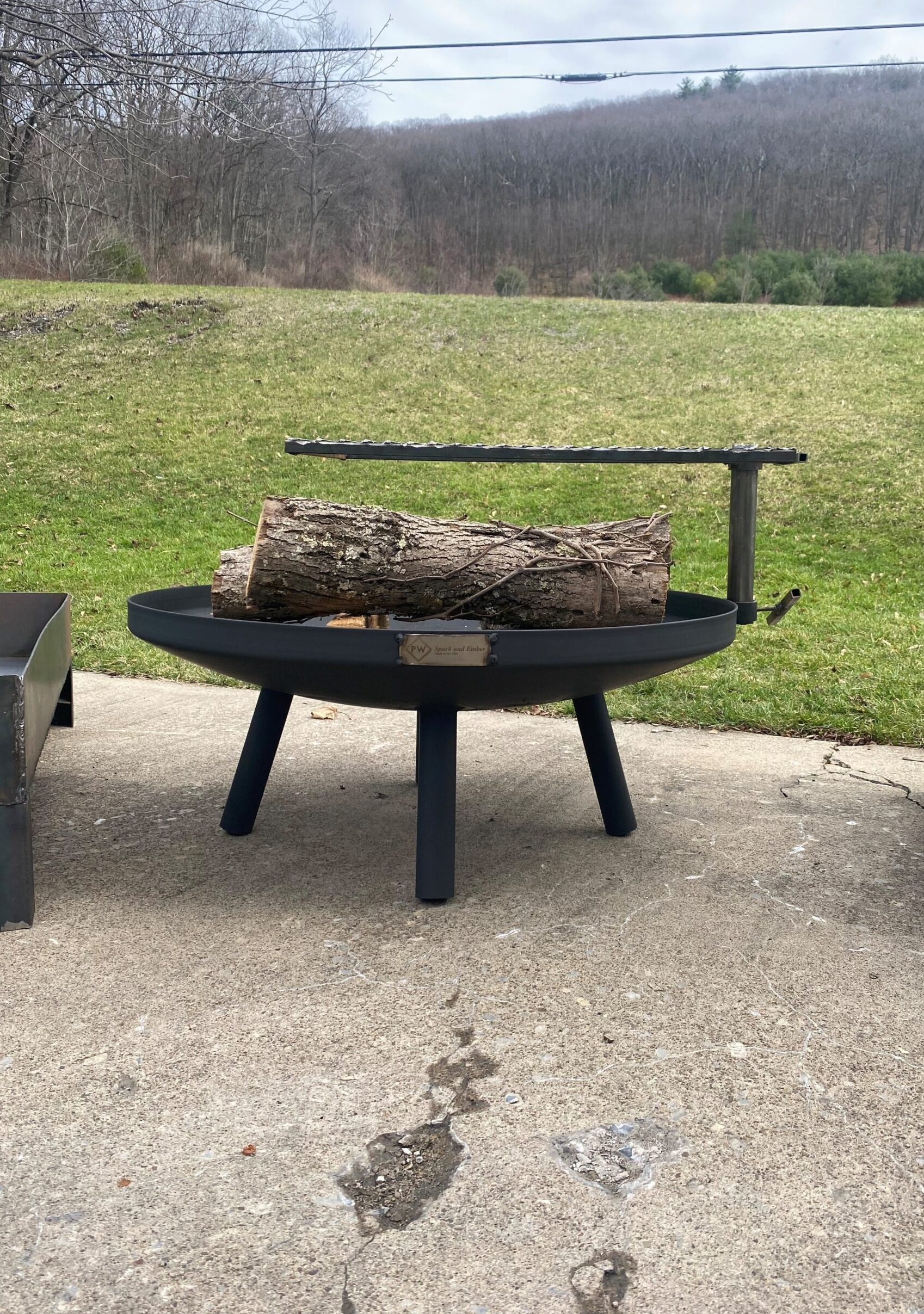 Round Firepit with a grilling grate, with a log on it
